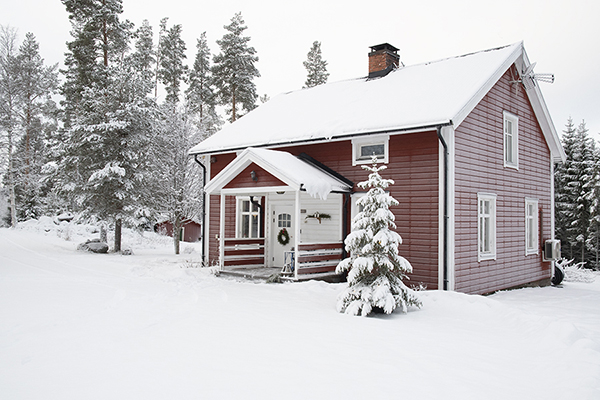 Huset en vacker vinterdag. En snöig gran står framför.